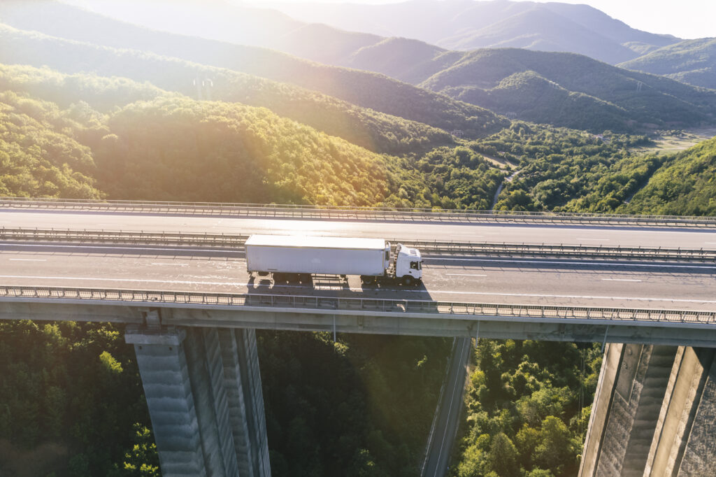 trucks on highway in mountain at sunset aerial view